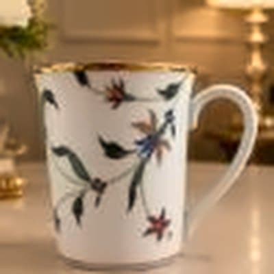 White mug with red and green floral sprigs and a gold rim
